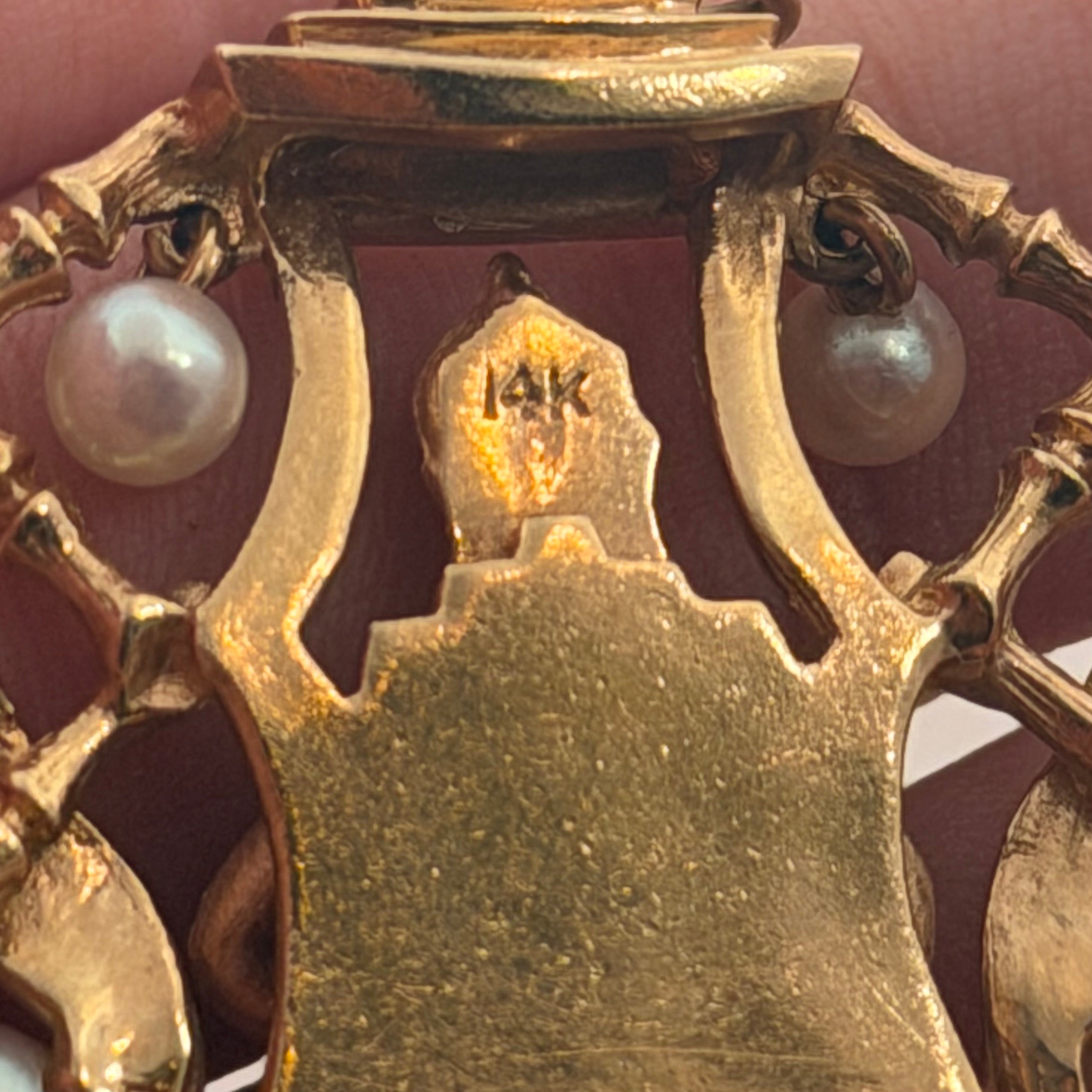 Close up of 14K stamp on the reverse of a vintage gold Buddha charm with pearls