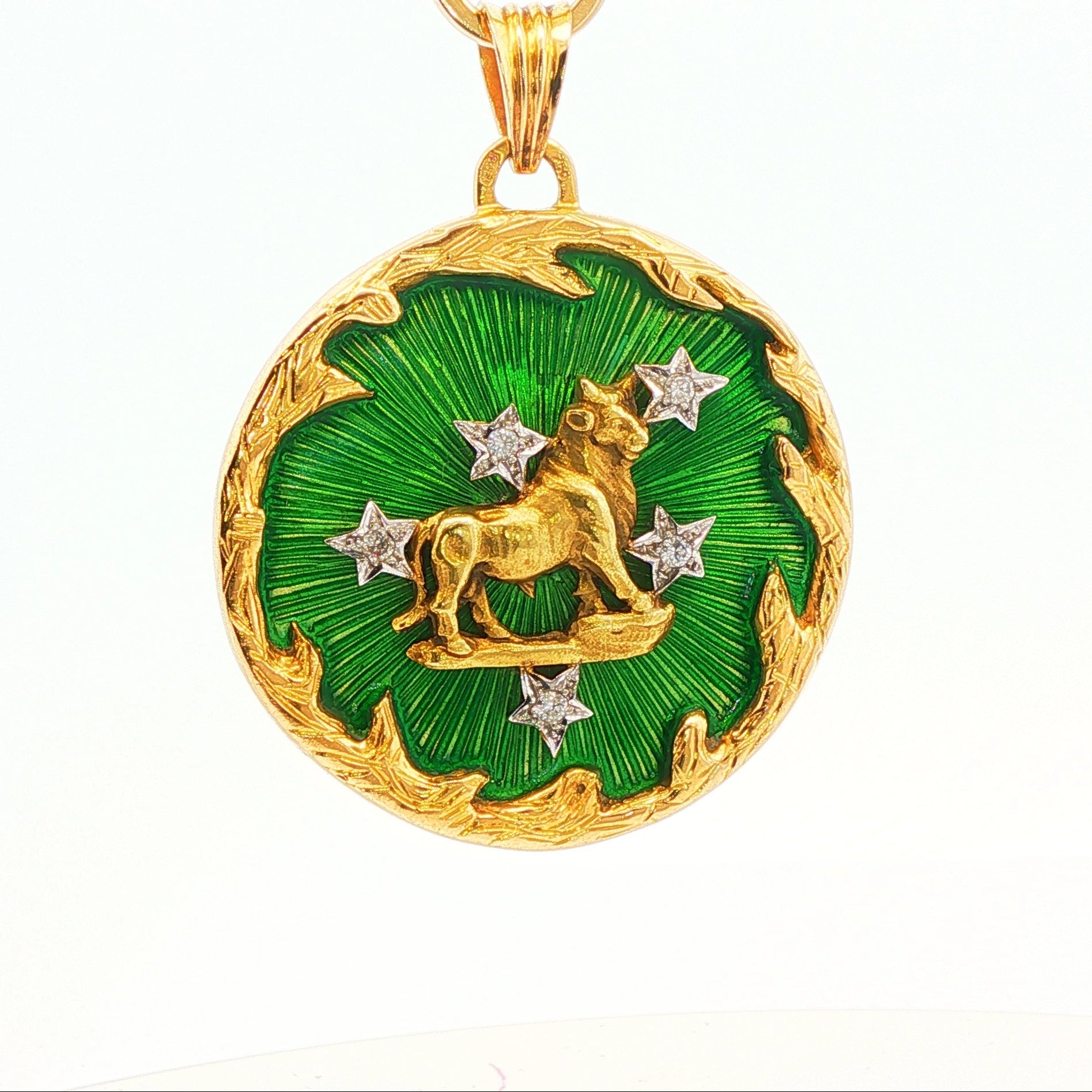 1970s 18 karat yellow gold Taurus zodiac pendant with green enamel, diamond accents, and a sculpted bull motif, shown in a straight front view