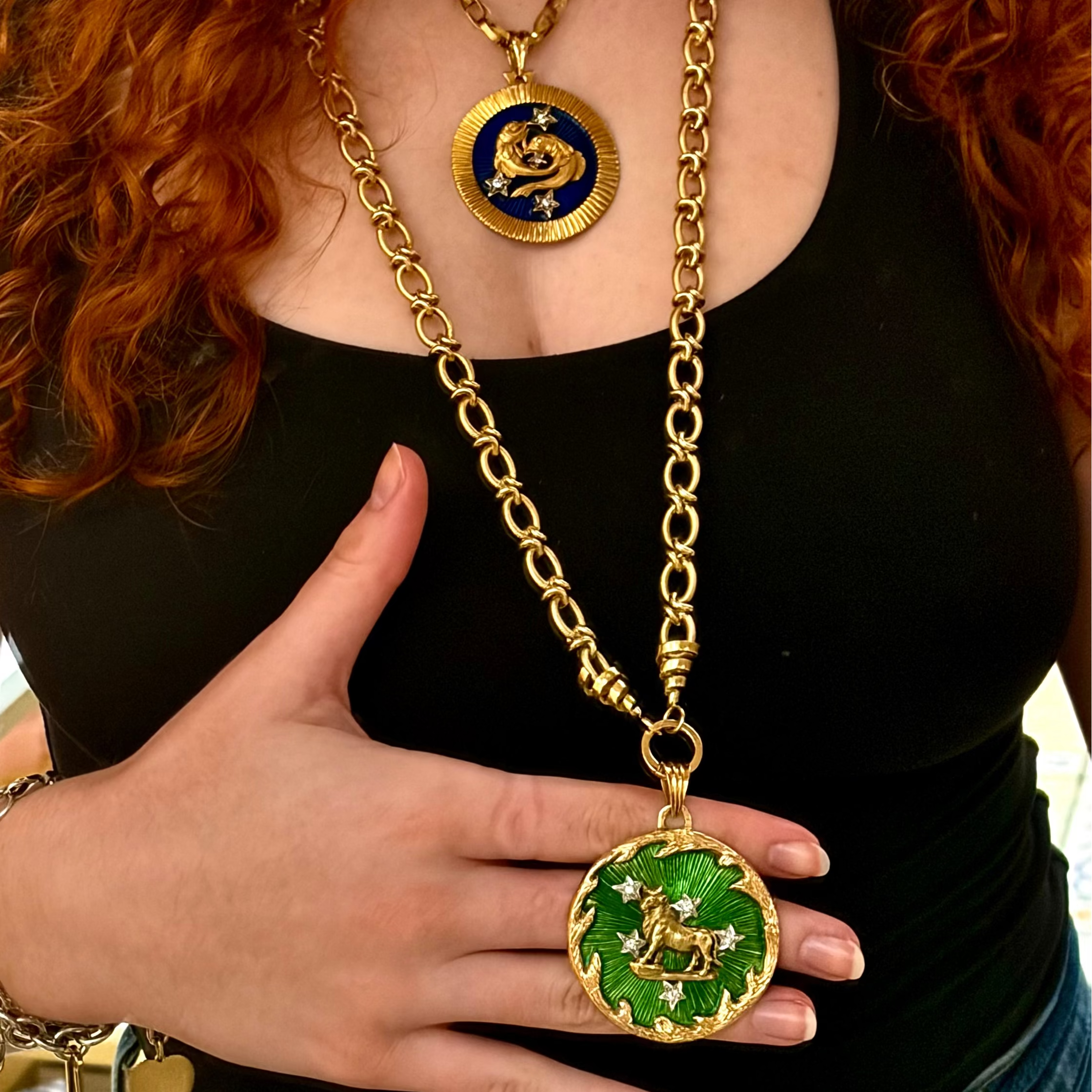Angled view of a 1970s 18 karat yellow gold Taurus pendant showing the raised bull relief, green enamel surface, and oversized medallion scale