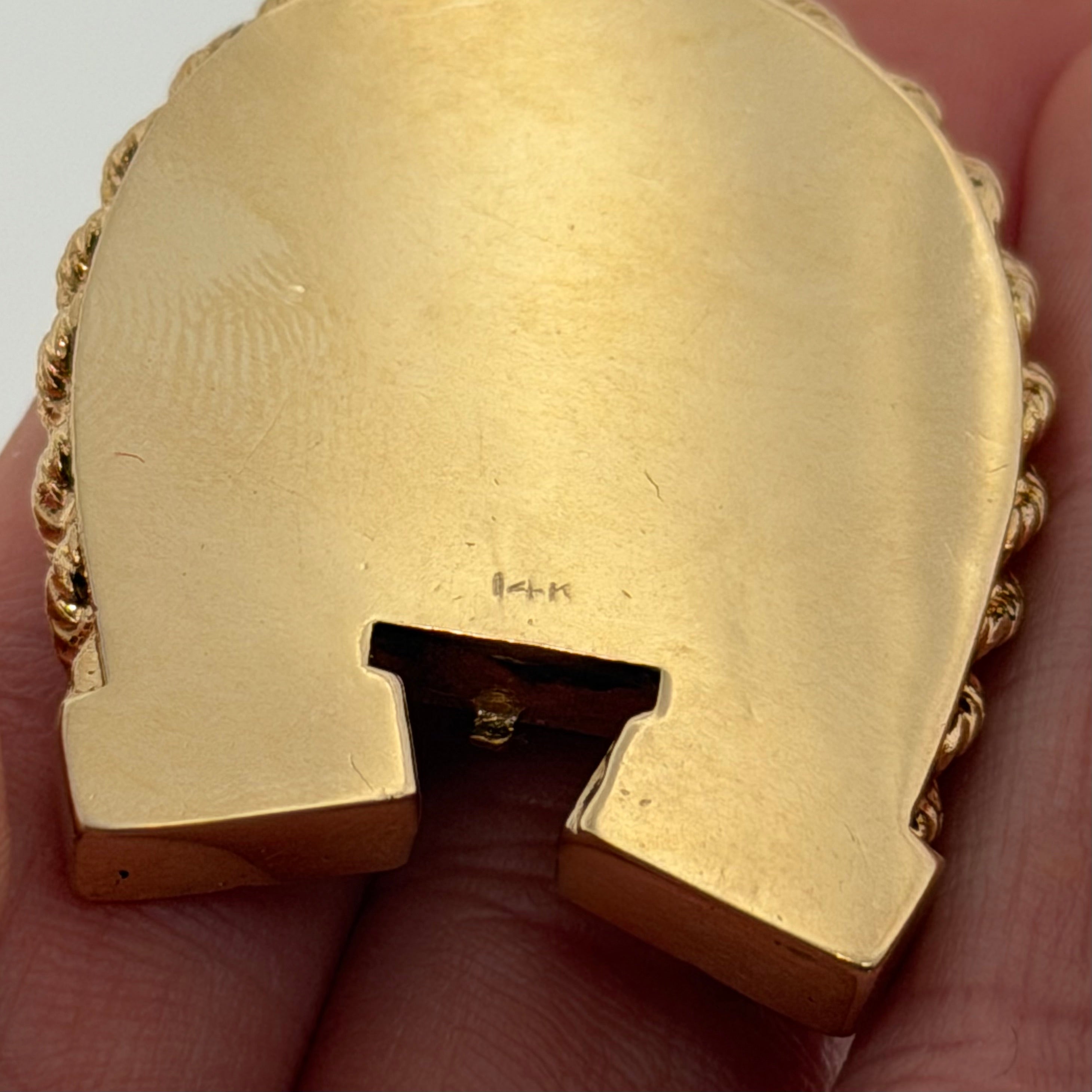 Close up of 14K stamp and hinge slot on the back of a vintage gold horseshoe locket