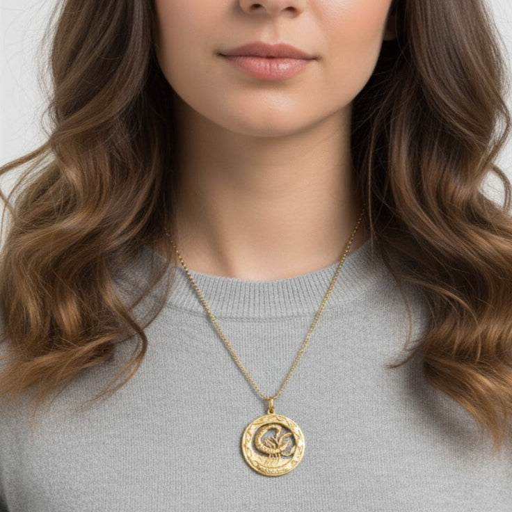Woman wearing a 14k gold scorpio charm with a gray sweater