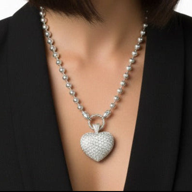 Woman wearing a black blazer with a pave heart-shaped pendant on a white background