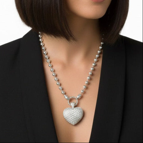 Woman wearing a black blazer with a pave heart-shaped pendant on a white background